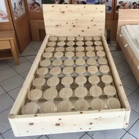 Holzbett mit innovativem Lattenrost aus runden, flexiblen Holzscheiben im Möbelgeschäft.